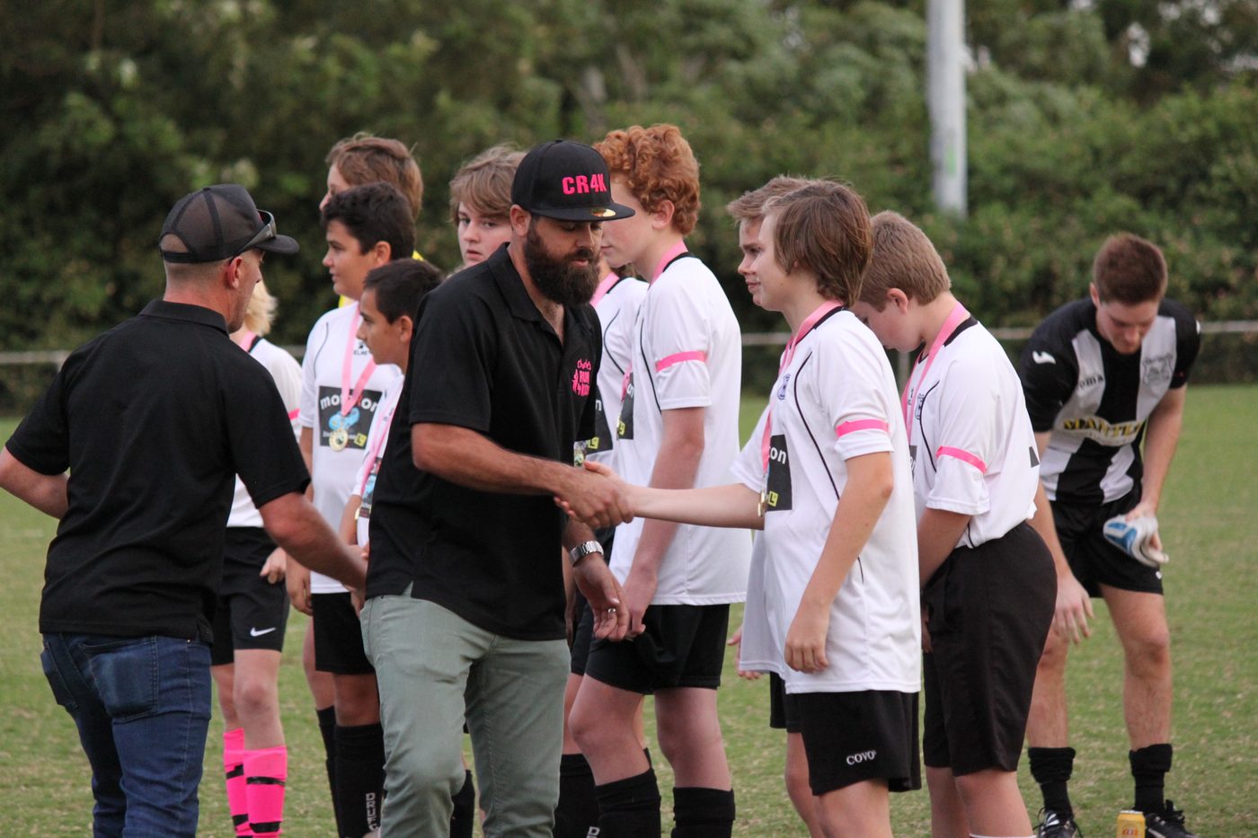 A Charlie's Run 4 Kids representative congratulating Dudley Redhead players at the Charlie Carr Cup